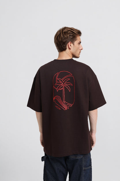 Man wearing a brown t-shirt with a red graphic on the back against a white background